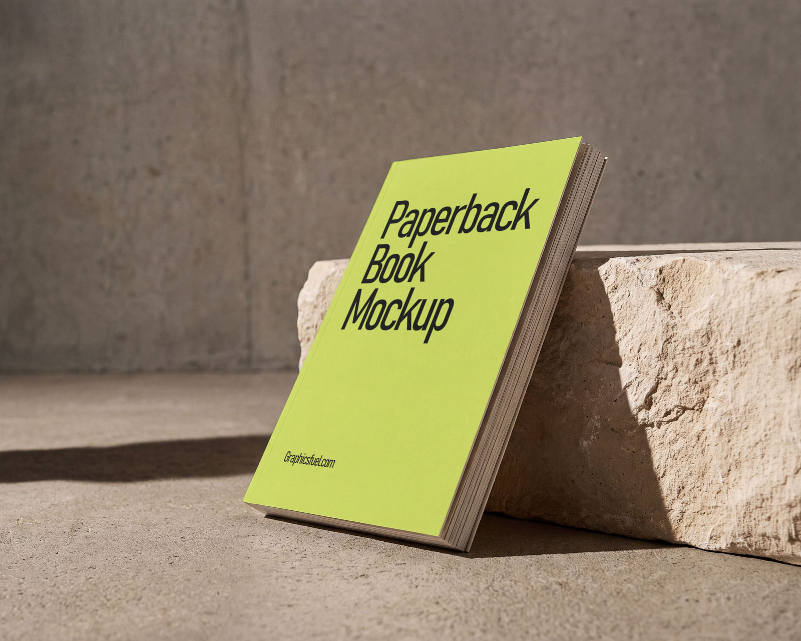 Paperback book mockup leaning against a limestone block with page edges visible