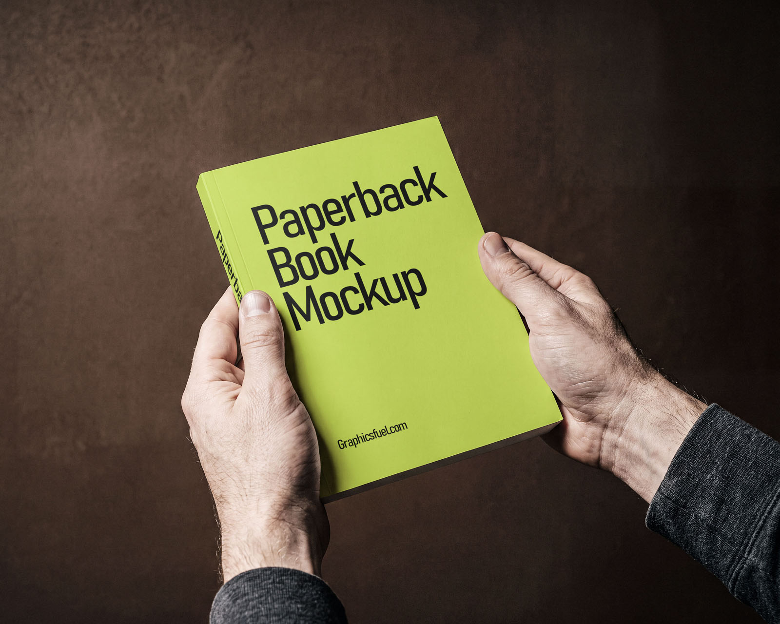 Paperback book mockup held in two hands at a three-quarter angle