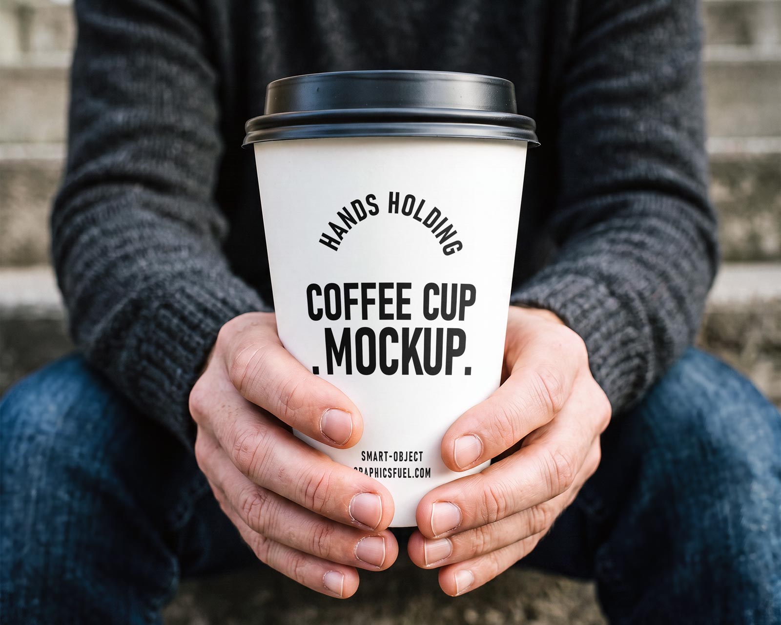 Hands holding a white paper coffee cup mockup outdoors on concrete steps